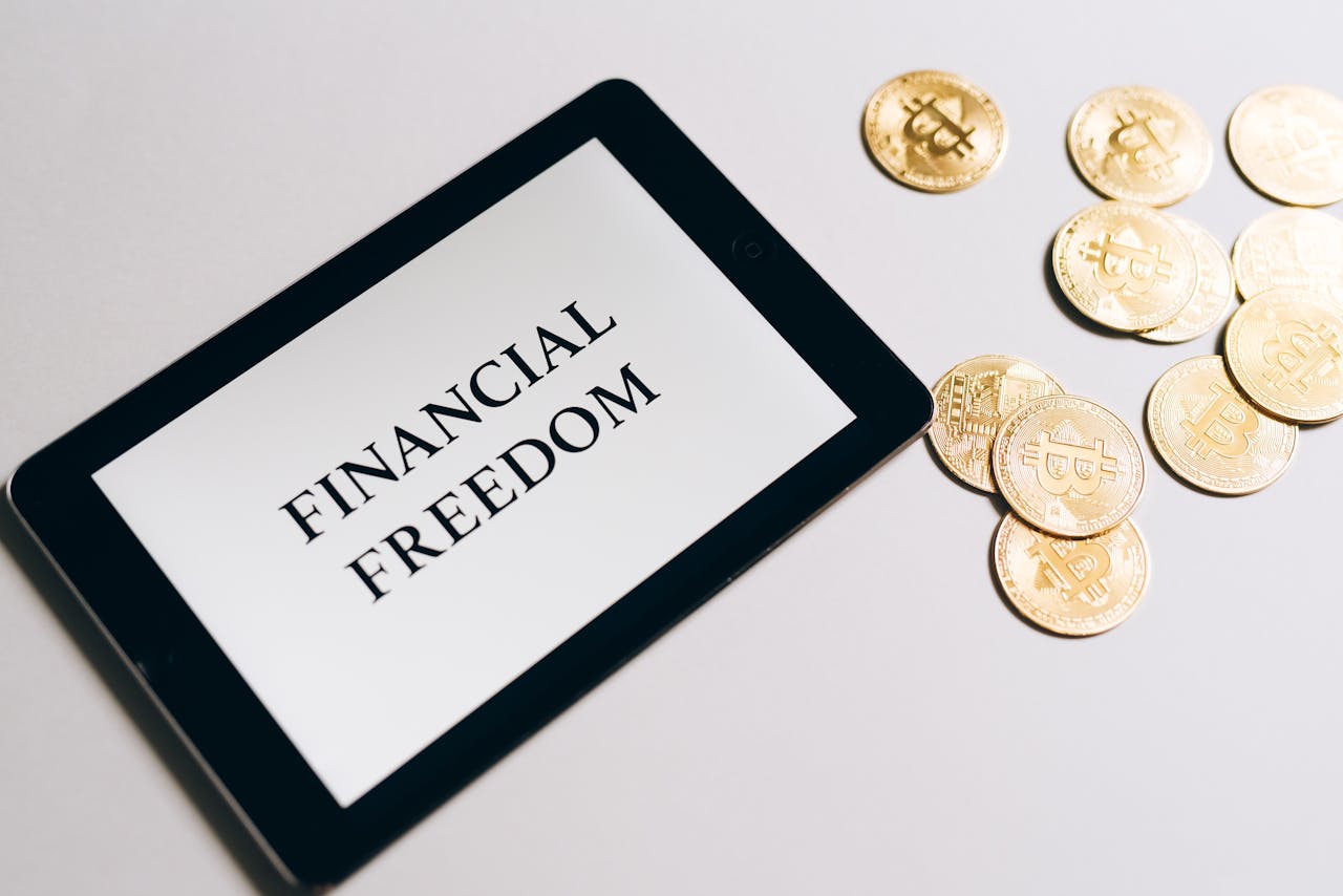 Tablet showing Financial Freedom with gold bitcoins nearby, symbolizing cryptocurrency investment.