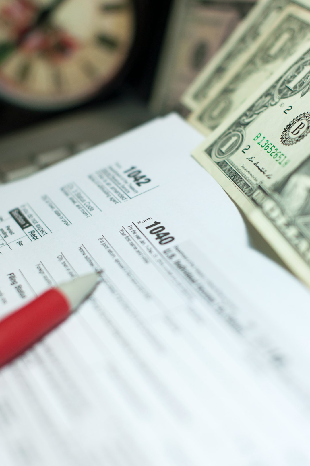 Tax Season: 1040 U.S. Individual Income Tax Return Form horizontal top view with an office laptop and blue calculator as background together with a red white pen preparation on taxation as foreground